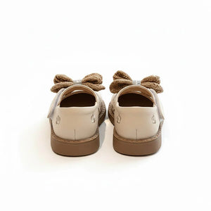 Back view of elegant baby girl shoes with beige bows and brown soles on white background