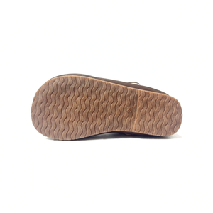 Brown sole of Mary Jane shoe with wavy tread pattern on white background